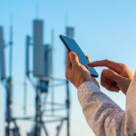 5G Communications Tower With Man Using Mobile Phone